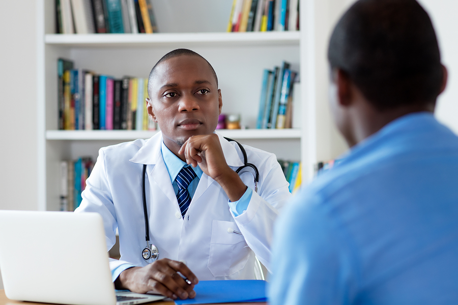 african american doctor listening to problems of male patient at